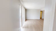 This 2-bedroom, 2-bathroom residence is designed for comfortable, efficient living on a single floor. The open-concept main area seamlessly combines the living room, dining room, and kitchen into one cohesive space. Light wood-look flooring runs throughout the common areas, complemented by neutral gray walls and a textured ceiling that adds subtle character. Large vertical-blind-covered sliding glass doors flood the living area with natural light and provide outdoor access. The galley-style kitchen features dark cabinetry, light speckled countertops, white appliances including a refrigerator and electric range, and a pass-through counter that connects to the living and dining area. A pantry provides additional storage. Both bedrooms are carpeted and finished with the same soft neutral palette, offering a quiet retreat. The primary bedroom is a well-proportioned room with its own walk-in closet equipped with built-in shelving and hanging rods. The second bedroom also benefits from natural light and closet access. The bathrooms are clean and functional, each featuring a tub-shower combination, a single vanity with light countertops, taupe cabinetry, and a large mirror. Three total closets throughout the residence ensure ample storage for everyday needs.