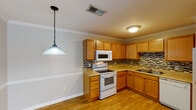 Located at 341 Guilford College Rd in Greensboro, NC, this single-floor home offers a well-organized layout with comfortable living spaces throughout. The kitchen is a functional highlight, featuring warm honey-toned wood cabinetry, a mosaic tile backsplash, light-colored countertops, and a full suite of white appliances including a range, over-the-range microwave, and dishwasher. Light hardwood flooring runs underfoot, and crown molding adds a refined touch. A pendant light fixture adds character to the space.

The bedrooms are generously proportioned, each finished with plush neutral carpet and equipped with ceiling fan light fixtures. Large windows allow natural light to filter in, offering views of surrounding trees. The rooms feature clean, neutral-toned walls with white trim, lending a bright and versatile canvas throughout.

The bathrooms are practical and well-appointed, featuring tub-shower combinations with chrome fixtures, vanities with single-basin sinks, and tile flooring. The overall floor plan, as seen from above, reveals a thoughtfully arranged single-level layout with clearly defined living, sleeping, and utility zones. The home presents a clean, move-in ready interior with consistent finishes throughout.