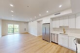 Unit 309 at 499 Atkinson Ave in Stoughton, Massachusetts is a thoughtfully designed one-bedroom, one-bathroom residence offering a clean, modern aesthetic throughout. Light-toned hardwood flooring flows seamlessly across the entire unit, complementing the crisp white walls and recessed lighting that brighten every room.

The open-concept kitchen and living area serves as the heart of the unit. The kitchen is outfitted with white shaker-style cabinetry, stainless steel appliances including a refrigerator, dishwasher, microwave, and range, and light countertops. The living area extends generously from the kitchen, offering access to a private balcony with a metal railing that overlooks a lush, tree-lined landscape.

The bedroom is well-proportioned, featuring a large window with treetop views, a ceiling light fixture, and a double-door closet. A stacked washer and dryer unit is conveniently tucked into the hallway, adding practical in-unit laundry access. The bathroom is clean and functional, finished in neutral tones with a shower and tub combination. Mini-split HVAC units are present in both the living area and bedroom, ensuring year-round climate control. The overall ambiance is bright, fresh, and move-in ready.