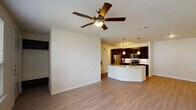 This one-bedroom, one-bathroom apartment in Conroe, TX offers a thoughtfully designed single-story layout that balances modern aesthetics with everyday functionality. The open-concept living and kitchen area is anchored by light wood-style flooring and a ceiling fan, creating a bright and airy atmosphere. The kitchen is a standout feature, showcasing rich dark cabinetry, granite countertops, a classic white subway tile backsplash, and stainless steel appliances including a range, microwave, and refrigerator. A curved peninsula with a sink and pendant lighting serves as both a functional workspace and a natural divider between the kitchen and living area. The living space is generously proportioned, offering ample room for comfortable furnishings, and benefits from natural light through multiple windows. The bedroom is carpeted for warmth and comfort, features a ceiling fan, a door leading to an outdoor balcony, and a spacious walk-in closet with built-in shelving. The full bathroom is well-appointed with dark cabinetry, dual granite-topped vanities, a large mirror, and a glass-enclosed tile shower. The overall design presents a clean, contemporary feel throughout.