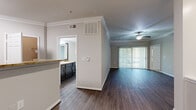 Located in Houston's Galleria area, this well-appointed 2-bedroom, 3-bathroom single-floor residence offers a thoughtful layout with quality finishes throughout. The open living room features rich hardwood-style flooring, crown molding, a ceiling fan, and a sliding glass door that fills the space with natural light and provides outdoor access. A decorative column adds an architectural touch to the living area. The kitchen is equipped with dark espresso cabinetry, granite-style countertops, stainless steel appliances including a refrigerator and microwave, and a peninsula that opens to the main living space. Both bedrooms are carpeted and feature ceiling fans and windows with outdoor views, creating comfortable, light-filled retreats. The generously sized primary bedroom includes a walk-in closet with wire shelving. The bathrooms are finished with dark vanity cabinetry, granite-style countertops, framed mirrors, and wood-style flooring. A dedicated laundry area houses a full-size Whirlpool washer and dryer. Two closets provide ample storage throughout the home. Neutral wall tones and consistent finishes tie the entire space together for a cohesive, move-in-ready feel.