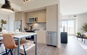 Located at 10135 108 Street NW in Edmonton, Alberta, this thoughtfully designed two-bedroom, two-bathroom residence offers a modern and cohesive aesthetic throughout. The open-concept living area is bathed in natural light through expansive floor-to-ceiling windows that frame striking panoramic views of the Edmonton skyline, creating an airy and spacious atmosphere. Wood-look plank flooring runs throughout, unifying the space with warmth and continuity.

The kitchen is a standout feature, showcasing light wood cabinetry, stainless steel appliances, a textured tile backsplash, and a marble-topped island with bar seating—ideal for both meal preparation and casual dining. A pendant light fixture adds a refined finishing touch.

Both bedrooms are well-proportioned and bright, each benefiting from natural light and city views through well-positioned windows. The primary bedroom offers a comfortable retreat with clean, neutral finishes.

The two bathrooms mirror the home's contemporary style, featuring light wood vanities, marble-topped counters, large-format tile flooring, and full-width mirrors. The hallway, accented with wood-grain floors and recessed lighting, connects all rooms with a clean, welcoming flow. This residence combines functional design with elevated modern finishes in a prime downtown location.