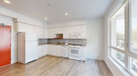 This efficiently designed 1-bedroom, 1-bathroom unit offers a thoughtfully arranged single-level floor plan that maximizes every square foot. Light-toned hardwood-style flooring runs throughout, lending a cohesive and airy feel to the entire space.

The kitchen is a standout feature, showcasing sleek white cabinetry extending to the ceiling for ample storage, complemented by a stylish mosaic tile backsplash in neutral tones. Warm-hued countertops provide a functional workspace, while white appliances — including a refrigerator, dishwasher, oven/range, and over-the-range microwave — complete the setup. Recessed lighting brightens the area effectively.

The living area flows directly from the kitchen, benefiting from a large window that invites natural light and frames an exterior view. The open layout creates a comfortable and versatile space.

The bedroom is a quiet, well-proportioned room finished in crisp white walls and the same light flooring. A sliding door leads to a built-in closet, offering convenient storage.

The bathroom features a full-size soaking tub with an overhead shower and curtain rod, a toilet, and a vanity, all set against clean white walls and matching flooring, creating a simple yet functional space.

Overall, the unit presents a bright, modern aesthetic with a clean, minimalist design sensibility.