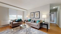 This thoughtfully designed single-floor residence offers a cohesive blend of modern finishes and comfortable living spaces. The living room serves as the heart of the home, featuring warm hardwood flooring, large windows that flood the space with natural light and offer pleasant outdoor views, and a clean, neutral color palette accented by teal decor touches. A glass-top coffee table and paired sofas create an inviting and functional seating arrangement.

The kitchen is outfitted with white shaker-style cabinetry, light quartz countertops, a subway tile backsplash, and stainless steel appliances, providing both style and practicality. The galley-style layout maximizes efficiency while maintaining an open, airy feel. Adjacent to the kitchen, the dining area benefits from large sliding glass doors that introduce abundant natural light and provide access to an outdoor space, complemented by a contemporary chandelier overhead.

The bedrooms are carpeted and serene, each receiving generous natural light through wide windows. They offer ample space for furnishings and personal touches. The bathroom is clean and bright, finished in crisp white with a shower-tub combination and accessibility-friendly grab bar. Throughout, the residence maintains a cohesive, modern aesthetic with neutral tones and quality finishes.