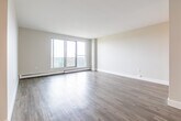 Located at 49 Vanier Dr in Kitchener, Ontario, this well-appointed 2-bedroom, 1-bathroom unit offers a clean, modern aesthetic throughout its thoughtfully laid-out single floor. Light-toned hardwood-style flooring runs consistently across the living spaces, complementing the neutral, softly painted walls that create a bright and welcoming atmosphere.

The spacious living room is bathed in natural light, opening onto a balcony through large sliding glass doors that frame views of the surrounding greenery — an inviting feature that extends the sense of space. Adjacent to the living area, the kitchen is well-equipped with white shaker-style cabinetry, a white subway tile backsplash, stainless steel appliances including a range, over-the-range microwave, dishwasher, and refrigerator, along with a double sink.

The primary bedroom is generously sized and features a large window that draws in ample natural light and outdoor views. The second bedroom is comfortably proportioned with its own window and sliding closet access. A dedicated walk-in style closet provides excellent storage. The full bathroom features grey tile flooring, a subway-tiled tub surround, a dark granite-topped vanity, and chrome fixtures. A connecting hallway ties all rooms together efficiently.