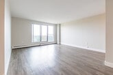 Located at 49 Vanier Dr in Kitchener, Ontario, this well-appointed 2-bedroom, 1-bathroom unit offers a clean, modern aesthetic throughout its thoughtfully laid-out single floor. Light-toned hardwood-style flooring runs consistently across the living spaces, complementing the neutral, softly painted walls that create a bright and welcoming atmosphere.

The spacious living room is bathed in natural light, opening onto a balcony through large sliding glass doors that frame views of the surrounding greenery — an inviting feature that extends the sense of space. Adjacent to the living area, the kitchen is well-equipped with white shaker-style cabinetry, a white subway tile backsplash, stainless steel appliances including a range, over-the-range microwave, dishwasher, and refrigerator, along with a double sink.

The primary bedroom is generously sized and features a large window that draws in ample natural light and outdoor views. The second bedroom is comfortably proportioned with its own window and sliding closet access. A dedicated walk-in style closet provides excellent storage. The full bathroom features grey tile flooring, a subway-tiled tub surround, a dark granite-topped vanity, and chrome fixtures. A connecting hallway ties all rooms together efficiently.