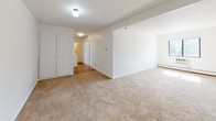 This 2-bedroom, 1-bathroom residence is thoughtfully arranged on a single floor, offering a clean and functional layout throughout. The living area features warm beige carpeting, crisp white walls, and a built-in closet, creating a comfortable and versatile space. Natural light filters in through blinds-fitted windows, complemented by baseboard heating units that run along the walls in multiple rooms.

Both bedrooms are generously proportioned, carpeted, and bright, each equipped with baseboard heaters and windows that bring in natural light. One bedroom includes a closet with bi-fold doors, providing ample storage.

The kitchen is efficiently designed with white cabinetry, dark granite-style countertops, a stainless steel sink, and a gas range. Warm wood-tone flooring adds a welcoming contrast to the white finishes, and overhead cabinetry maximizes storage space.

The bathroom features a classic mosaic tile floor in soft blue and white tones, a white vanity with an integrated sink, a medicine cabinet with mirror, and a baseboard heater. The light, neutral color palette throughout the space creates a cohesive and airy atmosphere, making this residence a practical and comfortable place to call home.