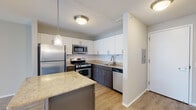 Located in Chicago's vibrant West Loop neighborhood, this modern residence at 180 N Jefferson Street offers a well-designed, open-concept layout filled with contemporary finishes throughout. Light-toned hardwood-style flooring flows seamlessly across the entire space, creating a cohesive and airy feel.

The kitchen is a standout feature, equipped with stainless steel appliances including a refrigerator, gas range, microwave, and dishwasher. White upper cabinetry is paired with rich dark lower cabinets, complemented by a classic white subway tile backsplash and granite countertops. A central island with additional storage and a granite surface provides both workspace and a natural gathering point, accented by a pendant light above.

The open living area is bathed in natural light through expansive floor-to-ceiling windows that frame striking views of the Chicago skyline, creating a bright and inviting atmosphere ideal for relaxing or entertaining.

The bathroom is finished with dark granite countertops, a dark wood vanity with under-sink storage, a framed mirror, and contemporary lighting fixtures, offering a clean and polished aesthetic.

Throughout the space, textured ceilings, neutral tones, and modern lighting fixtures contribute to a cohesive, contemporary ambiance that reflects the dynamic character of its downtown Chicago location.
