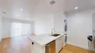 Located at 1806 N Berendo St in the desirable Los Feliz neighborhood of Los Angeles, this single-floor unit offers a clean, modern aesthetic with a thoughtfully designed open layout. Light hardwood flooring runs throughout the entire space, creating a warm and cohesive feel complemented by bright white walls and recessed lighting.

The open-concept kitchen serves as the heart of the unit, featuring sleek white cabinetry, a quartz waterfall-edge peninsula with an undermount sink, and a full suite of stainless steel appliances including a gas range, microwave, dishwasher, and French door refrigerator. A stacked washer and dryer unit is conveniently integrated into the kitchen area, maximizing functionality without sacrificing space.

The living area is generously proportioned, bathed in natural light from large sliding glass doors fitted with vertical blinds that open to an outdoor area, further enhancing the sense of openness. A separate bedroom offers privacy and comfort, equipped with a ceiling fan and a window with outdoor views, allowing natural light to fill the room.

The bathroom is finished with crisp white subway tile surrounding a full soaking tub and shower combination, complete with a built-in niche for storage. The overall design is minimal and contemporary, delivering a bright, move-in-ready living environment in one of LA's most vibrant neighborhoods.