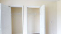 This single-floor space presents a clean and functional layout designed with practicality in mind. The interior is finished with warm, neutral-toned walls that create a calm and inviting ambiance throughout, complemented by crisp white door frames and trim that add a timeless, polished look.

A standout feature of the space is the dual closet configuration, where two adjacent closets are outfitted with built-in hanging rods, providing generous storage capacity for clothing and personal belongings. The closets are framed by classic white panel doors that blend seamlessly with the overall aesthetic. The neutral wall color and light, airy feel of the space make it highly versatile and easy to furnish or decorate to suit a variety of personal styles.

The flooring at the base of the closets appears to be carpeted, contributing to a softer, more comfortable underfoot experience. The overall design emphasizes simplicity and utility, with thoughtful built-in storage solutions that maximize the functionality of the available space. Whether used as a bedroom or private retreat, this space offers a well-considered foundation with storage, comfort, and a neutral palette that welcomes any aesthetic direction.