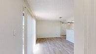 Located at 6424 Iron Horse Blvd in North Richland Hills, TX, this single-story residence offers a practical and comfortable layout with two bedrooms, two bathrooms, and two closets. The living area greets you with light wood-look plank flooring, neutral toned walls, and large vertical-blind windows that allow generous natural light to fill the space. A ceiling fan adds to the functionality of the open layout, which flows seamlessly into the kitchen area. The galley-style kitchen is outfitted with slate-gray cabinetry, a mosaic tile backsplash, white countertops, a stainless steel sink, and black appliances including a range and refrigerator. Both bedrooms feature soft carpeting, textured ceilings, and windows with blinds that offer natural light and exterior views. Each bedroom is served by its own dedicated closet. The two bathrooms are finished with matching gray cabinetry, white tub-shower combinations, and clean, light-toned flooring. The consistent use of neutral tones and cohesive finishes throughout creates a tidy, functional living environment well-suited for everyday comfort.