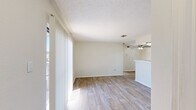Located at 6424 Iron Horse Blvd in North Richland Hills, TX, this single-story residence offers a practical and comfortable layout with two bedrooms, two bathrooms, and two closets. The living area greets you with light wood-look plank flooring, neutral toned walls, and large vertical-blind windows that allow generous natural light to fill the space. A ceiling fan adds to the functionality of the open layout, which flows seamlessly into the kitchen area. The galley-style kitchen is outfitted with slate-gray cabinetry, a mosaic tile backsplash, white countertops, a stainless steel sink, and black appliances including a range and refrigerator. Both bedrooms feature soft carpeting, textured ceilings, and windows with blinds that offer natural light and exterior views. Each bedroom is served by its own dedicated closet. The two bathrooms are finished with matching gray cabinetry, white tub-shower combinations, and clean, light-toned flooring. The consistent use of neutral tones and cohesive finishes throughout creates a tidy, functional living environment well-suited for everyday comfort.