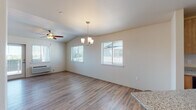 Located in Saint Helens, Oregon, this single-floor home offers a clean, modern interior with consistent wood-look flooring flowing throughout every room. The open living and dining area is a standout feature, showcasing vaulted ceilings, a ceiling fan, an elegant chandelier, and multiple windows that fill the space with natural light and offer pleasant outdoor views. A glass door leads out from the living area, further enhancing the connection to the outdoors.

The kitchen is equipped with warm-toned wood cabinetry, granite-style countertops, and black appliances including a Whirlpool refrigerator, electric range, and over-the-range microwave. A convenient breakfast bar provides additional seating and counter space.

Multiple bedrooms offer bright, neutral interiors with the same durable flooring, and at least one bedroom features a window with a tree-lined outdoor view. A central hallway connects the rooms efficiently, with additional storage spaces visible throughout.

The bathroom features a wood vanity with granite-style countertops, a tub/shower combination with clean white surrounds, and light tile flooring. The home's neutral color palette and updated finishes create a fresh, move-in-ready atmosphere throughout.