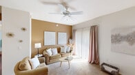 This thoughtfully designed single-floor residence offers a comfortable and cohesive layout with 1 bedroom and 1 bathroom. The living room serves as the heart of the home, featuring warm neutral-toned accent walls, plush carpeting, and a ceiling fan overhead. A sliding glass door floods the space with natural light, while the open layout connects seamlessly to both the dining and kitchen areas.

The kitchen is well-equipped with white cabinetry, dark countertops, white appliances including a refrigerator, electric range, and built-in microwave, all complemented by rich hardwood-style flooring. The adjacent dining area comfortably accommodates a round table and chairs, with a large decorative mirror enhancing the sense of space.

The bedroom is a serene retreat with soft carpet, a window dressed in sheer white curtains, and ample room to furnish comfortably. The bathroom features hardwood-style flooring, a shower with curtain, and clean white walls accented with decorative touches.

A welcoming entryway with carpeted flooring and bright white walls completes the unit. Throughout the space, warm neutral tones and consistent finishes create a cohesive, inviting ambiance ideal for comfortable everyday living.