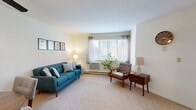 Located in Hales Corners, WI, this 2-bedroom, 1-bathroom residence offers a functional and comfortable single-floor layout. The combined living and dining area is bright and welcoming, with large windows that invite natural light and provide a warm, airy atmosphere. Soft carpeting runs throughout the main living spaces, complementing the neutral wall tones and creating a cohesive feel.

The kitchen features warm oak cabinetry, granite-style countertops, stainless steel appliances including a range and refrigerator, and a convenient pass-through counter that connects to the living area. The primary bedroom is a comfortable retreat with a window, carpet flooring, and access to generous closet space. The second bedroom is versatile, well-lit by a large window, and well-suited as a guest room or home office. The full bathroom includes a wood-toned vanity with stone-style countertops, tile flooring, and a walk-in shower.

With four closets distributed throughout the unit, storage is plentiful. A hallway connects the key areas of the home efficiently. The clean, understated design and practical layout make this residence a functional and inviting space in a residential Hales Corners neighborhood.