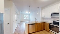 Located at 1 North Main Street in Port Chester, NY, this thoughtfully designed one-bedroom, one-bathroom residence offers a bright and modern living experience. Light wood-tone flooring flows seamlessly throughout the entire space, complementing the clean white walls and creating a cohesive, contemporary aesthetic.

The open-concept kitchen is a standout feature, equipped with stainless steel appliances including a refrigerator, range, and microwave. Two-tone cabinetry pairs warm wood lower cabinets with crisp white upper cabinets, accented by a classic subway tile backsplash. A peninsula with a quartz-style countertop and pendant lighting above serves as both a prep space and a visual divider between the kitchen and the living area. The adjoining living area is bright and open, benefiting from a window that brings in natural light and neighborhood views.

The bedroom is a comfortable, well-proportioned retreat with a large window overlooking the surroundings, filling the room with natural light. A dedicated walk-in closet with wire shelving and hanging rods provides ample storage.

The bathroom is finished in a clean, modern style with large-format floor tiles, a soaking tub with subway tile surround, a wood-toned vanity with a white countertop, and an illuminated mirror, completing this well-appointed residence.