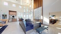 Located at 4407 Hopson Rd in Morrisville, NC, this contemporary single-floor clubhouse is thoughtfully designed to serve as a dynamic social and professional hub. The grand entrance lobby immediately impresses with soaring ceilings, dramatic vertical pendant lighting, and a sleek, high-gloss blue reception desk set against a striking textured stone accent wall framed in warm wood paneling. Floor-to-ceiling windows flood the space with an abundance of natural light and offer views of the surrounding community. A bright sunroom-style lounge area features expansive multi-pane windows, navy blue accent chairs, and an open, airy atmosphere. Enclosed private workspaces with glass-paneled doors provide quiet areas for focused work, while a cozy banquette nook and casual seating areas with warm amber chairs offer inviting spots for conversation. The game room is well-appointed with a billiards table, shuffleboard, wall-mounted displays, and stylish wallpaper accents. A fully equipped kitchen and social bar area showcases a marble waterfall island, dramatic clustered pendant lighting, and a navy tile feature wall with built-in media display. Throughout, light wood-tone flooring, curated contemporary artwork, and a cohesive blue-and-neutral palette create a polished, welcoming ambiance.