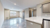 Located at 1812 Bourbon St in Ashville, OH, this single-floor unit offers a thoughtfully designed layout that maximizes functionality. The open-concept living area seamlessly integrates the living room, dining space, and kitchen, all finished with striking polished concrete floors that lend a modern, industrial character throughout. The kitchen is well-equipped with gray shaker-style cabinetry, marble-look quartz countertops, a full suite of stainless steel appliances including a dishwasher, range, microwave, and refrigerator, and a peninsula with additional counter space. Recessed lighting illuminates the main living area, which also features a patio door leading to one of two outdoor patio spaces. The bedroom offers a ceiling fan, a large window with natural light and exterior views, and access to generous closet storage with wire shelving systems. The bathroom includes a full tub-and-shower combo with brushed nickel fixtures. A dedicated in-unit laundry area houses a full-size washer and dryer. Additional utility and storage spaces round out the practical layout, making this a comprehensive and efficiently organized living space.