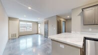 Located at 1812 Bourbon St in Ashville, OH, this single-floor unit offers a thoughtfully designed layout that maximizes functionality. The open-concept living area seamlessly integrates the living room, dining space, and kitchen, all finished with striking polished concrete floors that lend a modern, industrial character throughout. The kitchen is well-equipped with gray shaker-style cabinetry, marble-look quartz countertops, a full suite of stainless steel appliances including a dishwasher, range, microwave, and refrigerator, and a peninsula with additional counter space. Recessed lighting illuminates the main living area, which also features a patio door leading to one of two outdoor patio spaces. The bedroom offers a ceiling fan, a large window with natural light and exterior views, and access to generous closet storage with wire shelving systems. The bathroom includes a full tub-and-shower combo with brushed nickel fixtures. A dedicated in-unit laundry area houses a full-size washer and dryer. Additional utility and storage spaces round out the practical layout, making this a comprehensive and efficiently organized living space.