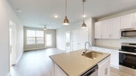 Located at 6015 Mar Dhea Lane in Charlotte, NC, this well-appointed 2-bedroom, 2-bathroom home offers a thoughtfully designed single-level layout with modern finishes throughout. The open-concept living area seamlessly connects the kitchen, dining, and living spaces, creating an inviting atmosphere filled with natural light from multiple windows. The kitchen is a standout feature, showcasing white shaker cabinetry, quartz countertops, stainless steel appliances, a subway tile backsplash, and a central island with pendant lighting and an undermount sink — ideal for both cooking and entertaining. Light wood-look flooring flows throughout the main living areas, adding warmth and cohesion to the space. The primary bedroom offers generous proportions, plush carpeting, and a ceiling fan, with an en-suite bathroom featuring a dual-sink vanity with quartz countertops, white cabinetry, a walk-in shower with marble-style tile, and direct access to a walk-in closet. The second bedroom is equally comfortable, with soft carpet, a ceiling fan, and ample natural light. A private balcony extends the living space outdoors. Additional highlights include four closets, in-unit laundry, and a utility room for added convenience.