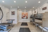 Located at 3400 Winterset Pkwy SE in Marietta, Georgia, this pet grooming facility is thoughtfully designed to provide a clean, functional, and welcoming environment for pets and their owners. The single-floor space is finished throughout with classic white subway tile walls, light wood-look tile flooring, and recessed lighting, creating a bright and hygienic atmosphere.

The facility is divided into two primary functional zones. The bathing area features multiple stainless steel grooming tubs equipped with professional-grade spray attachments, built-in steps for easy pet access, and white cabinetry for supply storage. Anti-fatigue rubber mats are positioned strategically for safety and comfort.

The grooming area is outfitted with adjustable height grooming tables and a wall-mounted professional dryer arm, allowing for efficient and thorough grooming sessions. Large black-framed windows flood this area with natural light and offer views of the surrounding greenery, creating an open and airy feel.

Throughout the space, playful pet-themed artwork and signage — including a charming "Pets Are" wall mural — add warmth and personality. The facility includes a secure entry door with keypad access, ensuring a controlled and safe environment. Overall, the space combines practical, professional-grade equipment with a clean and cheerful aesthetic.