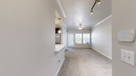 This single-story, one-bedroom, one-bathroom residence offers a thoughtfully designed open-concept layout that maximizes its comfortable footprint. The living room is finished with plush carpet, crown molding, and a ceiling fan, while track lighting adds a modern touch. A large glass door opens to an outdoor area, allowing natural light to fill the space. The kitchen is accessible via a pass-through peninsula with a white countertop, creating seamless connectivity to the living area. Inside, the kitchen features rich dark wood cabinetry, a classic white subway tile backsplash, light tile flooring, stainless steel appliances including a refrigerator, electric range, and built-in microwave, plus a full-sized pantry enclosed by double doors. The bedroom is generously sized, carpeted, and highlighted by a striking arched window that frames outdoor views, complemented by a ceiling fan. It connects directly to a spacious walk-in closet outfitted with multi-tiered wire shelving and hanging rods. The bathroom includes a dark wood vanity with a white countertop, tile flooring, and a glass-enclosed walk-in shower with tile surround, offering a clean, functional design throughout.