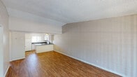 This single-floor unit offers a practical and straightforward layout designed for comfortable everyday living. The open living and dining area is a standout feature, characterized by painted concrete block walls that lend a distinct architectural texture, warm hardwood-style flooring, and a textured ceiling throughout. A sliding glass door at the far end of the living area fills the space with natural light and provides direct outdoor access.

The kitchen is efficiently arranged in a U-shape, featuring white cabinetry, dark granite-style countertops, a stainless steel sink, and white appliances including an electric range and over-the-range microwave. A peninsula-style counter separates the kitchen from the main living area, enhancing the open-plan feel.

A central hallway connects the living areas to the private spaces of the unit. The bedroom is generously sized, finished with plush carpet, painted brick-textured walls, a textured ceiling, and a window with vertical blinds for light control.

Two full bathrooms serve the unit, each featuring hardwood-style flooring, white vanities, and a tiled shower-and-tub combination. The consistent use of warm flooring and neutral tones throughout creates a cohesive and clean aesthetic across the entire space.