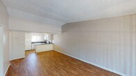 This single-floor unit offers a practical and straightforward layout designed for comfortable everyday living. The open living and dining area is a standout feature, characterized by painted concrete block walls that lend a distinct architectural texture, warm hardwood-style flooring, and a textured ceiling throughout. A sliding glass door at the far end of the living area fills the space with natural light and provides direct outdoor access.

The kitchen is efficiently arranged in a U-shape, featuring white cabinetry, dark granite-style countertops, a stainless steel sink, and white appliances including an electric range and over-the-range microwave. A peninsula-style counter separates the kitchen from the main living area, enhancing the open-plan feel.

A central hallway connects the living areas to the private spaces of the unit. The bedroom is generously sized, finished with plush carpet, painted brick-textured walls, a textured ceiling, and a window with vertical blinds for light control.

Two full bathrooms serve the unit, each featuring hardwood-style flooring, white vanities, and a tiled shower-and-tub combination. The consistent use of warm flooring and neutral tones throughout creates a cohesive and clean aesthetic across the entire space.