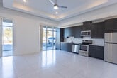 Located at 410 Thorn Ave in El Paso, TX, this single-floor space offers a clean, modern aesthetic characterized by consistent large-format tile flooring, bright white walls, and a well-considered layout. The open-concept living and kitchen area serves as the heart of the space, anchored by a tray ceiling with recessed lighting and a ceiling fan that adds both style and functionality. Expansive sliding glass doors flood the area with natural light and provide direct views of the exterior surroundings.

The kitchen is thoughtfully appointed with dark wood-grain cabinetry extending to the ceiling for ample storage, complemented by stainless steel appliances including a refrigerator, range, microwave, and dishwasher. Light countertops contrast cleanly against the cabinetry, reinforcing the modern design language.

A dedicated bedroom features its own ceiling fan, a bright window with blinds, and the same polished tile flooring, creating a calm and airy retreat. A closet with double doors provides generous built-in storage. The bathroom is finished in a minimalist style, featuring large-format tile, a walk-in shower with glass sliding doors, a vanity with dark cabinetry, and clean white fixtures. A hallway connects the private areas of the unit, lined with recessed lighting for a polished, uncluttered feel.