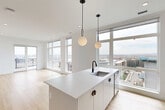 Located in Denver's West Colfax neighborhood, this contemporary 2-bedroom, 3-bathroom residence offers a sleek, modern design across a well-appointed single floor. The open-concept kitchen and living area serves as the heart of the home, anchored by a large center island with a white quartz countertop, undermount sink, and matte black fixtures. Pendant globe lights hang above the island, while floor-to-ceiling windows flood the space with natural light and frame expansive views of the Denver skyline and surrounding cityscape. The kitchen features white cabinetry, a light blue tile backsplash, stainless steel appliances, and light hardwood flooring that extends throughout the main living areas. The living room opens to a private balcony with striking city views. Both bedrooms are carpeted and generously sized, with the primary bedroom offering built-in wardrobe storage. The bathrooms are finished with clean, modern fixtures, including matte black hardware, a dual-vanity in one bath, a glass-enclosed shower, and a tiled soaking tub in another. A stacked in-unit washer and dryer add everyday convenience. The overall aesthetic is clean, bright, and contemporary throughout.