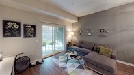 Located at 4209 E Beltline Ave NE in Grand Rapids, Michigan, this single-floor residence offers a thoughtfully designed layout that balances functionality with contemporary style. The open living area is anchored by warm wood-look flooring and a large sliding glass door that fills the space with natural light and provides direct access to a private patio, creating a seamless indoor-outdoor connection.

The kitchen is well-equipped for everyday living, featuring white shaker-style cabinetry with matte black hardware, dark granite countertops, stainless steel appliances including a gas range, microwave, and refrigerator, and a sink positioned along the perimeter for efficient workflow. The galley-style layout maximizes the available space while maintaining an organized, clean aesthetic.

Two bedrooms offer comfortable retreats, each with plush carpeting, neutral wall tones, and windows that allow natural light. The vaulted ceiling detail in the bedrooms adds a sense of openness. Both bathrooms are finished consistently with white vanity cabinetry, dark granite countertops, large mirrors, and wood-look flooring, with one bathroom featuring a subway tile surround. In-unit laundry with a full-size washer and dryer adds everyday convenience to this well-rounded residence.