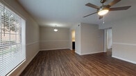 This 1-bedroom, 1-bathroom unit offers a thoughtfully designed single-floor layout that maximizes both comfort and functionality. Rich, dark hardwood-style flooring runs throughout the entire space, creating a cohesive and polished aesthetic from room to room.

The open living area is bright and welcoming, featuring large windows with blinds that allow abundant natural light to fill the space while offering views of the surrounding greenery. A ceiling fan with a built-in light fixture provides both comfort and illumination, while a decorative pendant light adds a subtle design touch. A chair rail detail along the walls adds a classic architectural element to the living space.

The galley-style kitchen is efficiently arranged with white shaker cabinetry, granite-look countertops, a stainless steel sink, and black appliances including a refrigerator, stove, and dishwasher — providing everything needed for everyday meal preparation.

The bedroom is generously sized, featuring a ceiling fan, a window for natural light, and a closet with sliding panel doors that open to a well-organized storage space.

The bathroom is clean and modern, appointed with a white vanity, granite-look countertop, and a tub-shower combination with tiled surround — completing this move-in-ready unit with practical, updated finishes throughout.