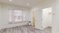 Located on Franklin Avenue in the heart of Los Angeles, CA, this efficiently designed studio offers a thoughtfully organized single-floor layout comprising a living area, bathroom, and closet. The interior features light gray luxury vinyl plank flooring throughout, creating a cohesive and contemporary look that runs seamlessly from room to room. Crisp white walls, white panel doors, and recessed lighting contribute to the bright, clean ambiance of the space.

The main living area is open and well-lit, benefiting from natural light through windows dressed with white horizontal blinds. A wall-mounted HVAC vent provides climate control, supplemented by a portable air conditioning unit. A compact kitchenette is integrated into the space, outfitted with white cabinetry, a stainless steel mini-refrigerator, a microwave, and a small sink — providing essential cooking conveniences.

A dedicated closet with built-in shelving offers practical storage solutions. The bathroom is neatly appointed with light gray vinyl plank flooring matching the rest of the unit, a white pedestal-style vanity with a round mirror, a toilet, and a tiled walk-in shower. Overhead vanity lighting ensures the bathroom is well-illuminated. The overall design is modern, minimal, and move-in ready.