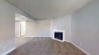 This single-floor residence offers a thoughtfully designed layout with a clean, neutral palette and a blend of comfort and functionality throughout. The spacious living room serves as the heart of the home, featuring plush carpeting, a white-surround fireplace, and large windows that allow ample natural light to fill the space. Distinctive arched doorways lend an elegant architectural touch, connecting the living and dining areas to the rest of the home. The kitchen is well-equipped with white cabinetry, stainless steel appliances including a dishwasher, light wood-style vinyl flooring, and a window above the sink that brings in additional natural light. The bedrooms are carpeted and generously sized, each with vertical-blind sliding doors that open to outdoor access and ceiling fans for added comfort. The bathroom features a single vanity with white cabinetry, a neutral countertop, and a mirrored medicine cabinet with overhead lighting. A dedicated laundry area includes a full-size washer and dryer with overhead storage cabinets. A separate vanity area provides additional convenience. Throughout the space, textured ceilings, clean white trim, and consistent neutral tones create a cohesive and inviting atmosphere.