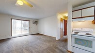 Located at 1865 Northway Dr in North Mankato, MN, this two-bedroom, one-bathroom unit offers a straightforward single-floor layout designed for comfortable everyday living. The carpeted living room is bright and open, featuring a ceiling fan, a wall-mounted air conditioning unit, a baseboard heater, and a sliding glass door that opens to a private balcony with outdoor views. The kitchen is efficiently arranged in an L-shaped configuration, outfitted with cream-colored cabinetry trimmed in warm wood tones, a white electric range, dishwasher, refrigerator, and a tile-style floor. A skylight adds a touch of natural brightness to the kitchen area. Both bedrooms are carpeted and include sliding-door closets for storage, with baseboard heating ensuring year-round comfort. The primary bedroom is generously sized and features a window that brings in natural light. The full bathroom is clean and functional, complete with a tub-shower combination, a vanity with under-sink storage, a mirrored medicine cabinet, and tile-style flooring that complements the kitchen. Warm wood-toned doors and trim are consistent throughout the unit, lending a cohesive, classic aesthetic to the overall space.