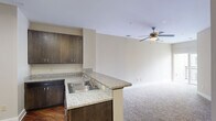 Located at 927 W Morgan St in Raleigh, NC, this single-floor, one-bedroom, one-bathroom residence offers a thoughtfully designed layout that maximizes every square foot. The open-concept kitchen is a standout feature, boasting rich dark-stained cabinetry, granite countertops, and a full suite of stainless steel appliances including a refrigerator, range, and over-the-range microwave. Track lighting overhead and a peninsula with bar seating create a functional yet stylish space that flows seamlessly into the carpeted living area, which features a ceiling fan with light fixture. Hardwood-style flooring in the kitchen transitions cleanly into the main living area. The bedroom is generously sized with plush carpet flooring, multiple windows fitted with plantation shutters allowing ample natural light, and direct access to an adjacent space. A dedicated pantry and closet provide excellent storage. The full bathroom is elegantly finished with large-format tile flooring, a tiled soaking tub and shower combination, a dual-sink vanity topped with granite, and a well-lit mirror. A walk-in closet accessible from the bathroom offers built-in shelving for organized storage. The neutral color palette throughout lends a clean, versatile aesthetic to the entire residence.