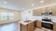 Located in Colorado Springs, CO, this single-floor residence offers a thoughtfully designed layout with 2 bedrooms and 2 bathrooms. The open-concept kitchen and living area serves as the heart of the home, featuring warm-toned cabinetry, light granite-style countertops, a peninsula with a double-basin stainless steel sink, and a full suite of stainless steel appliances including a refrigerator, electric range, microwave, and dishwasher. Recessed lighting and light wood-look flooring throughout the main living area create a bright, clean aesthetic. The primary bedroom is a generously sized retreat with plush carpet, a walk-in closet with built-in shelving, and recessed lighting. The second bedroom also features carpet, a large window with outdoor greenery views, and ample natural light. Both bathrooms are finished with matching cabinetry, granite-style countertops, undermount sinks, and wood-look flooring. Neutral warm tones throughout the home provide a cohesive and inviting atmosphere. The overall design balances practicality with modern style, making this Colorado Springs residence a comfortable and functional living space.