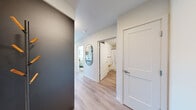 Located at 513 1st Ave N in Seattle's vibrant Lower Queen Anne neighborhood, this thoughtfully designed one-bedroom, one-bathroom unit offers an efficient and stylish layout with impressive views. The open-concept kitchen and living area serves as the heart of the home, where light wood-toned upper cabinetry contrasts with sleek dark lower cabinets. The kitchen features quartz countertops, a stainless steel sink with a matte black pull-down faucet, a tile backsplash, and stainless steel appliances including a dishwasher, range, and microwave. Light hardwood-style flooring flows throughout the entire unit, enhancing the bright, cohesive aesthetic. The living room is bathed in natural light from large floor-to-ceiling windows that frame breathtaking views of Puget Sound and the iconic Seattle Space Needle, creating a striking focal point. The bedroom offers a tranquil retreat with expansive corner windows overlooking the city and waterfront, along with a sliding-door closet for ample storage. A well-appointed hallway with an oval accent mirror connects the rooms to the full bathroom, which features a soaking tub and shower combo, a dark-toned vanity with white countertop, and matte black hardware throughout.