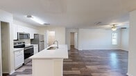 This 960-square-foot, single-floor apartment at MacAlpine Place features 2 bedrooms and 1 bathroom with a cohesive, modern design. Wood-style plank flooring runs throughout the entire unit, providing a clean, uniform aesthetic. The open-concept kitchen and living area serves as the heart of the home, anchored by a large island with a built-in sink and white quartz countertops. White shaker cabinets and stainless steel appliances—including a range, microwave, and refrigerator—complete the functional kitchen. The living room is bright and spacious, featuring multiple windows with natural light and a ceiling fan. Both bedrooms are well-proportioned, each equipped with ceiling fans; the primary bedroom measures 160 square feet and includes a dedicated closet with wire shelving. The full bathroom offers a white vanity with quartz countertop, a tub-shower combination with tile surround, and wood-style tile flooring. A dedicated laundry room houses an in-unit washer with wire shelving above for additional storage. A separate closet provides further organization space, rounding out this efficiently designed apartment.