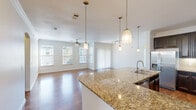 This well-appointed 4-bedroom, 3-bathroom home offers a thoughtfully designed single-floor layout that maximizes comfort and functionality. The open-concept kitchen and living area serves as the heart of the home, featuring rich hardwood flooring, a large granite island with an undermount sink, elegant pendant lighting, and dark espresso cabinetry paired with stainless steel appliances. A track lighting system and ceiling fan complete the space, while multiple windows flood the living area with abundant natural light and views of the outdoors.

The primary bedroom is generously sized, featuring hardwood floors, a ceiling fan, and multiple windows that bring in plenty of natural light. It is complemented by a spacious walk-in closet with built-in shelving and hanging rods. Additional bedrooms are finished with plush carpet, ceiling fans, crown molding, and built-in closet storage. The bathrooms are well-finished, highlighted by tile-surround soaking tubs with shower combinations and dark-framed cabinetry. A dedicated laundry room houses a full-size washer with overhead shelving for added convenience. Carpeted stairs with a wood handrail connect the levels, and three hallways ensure smooth circulation throughout the home.