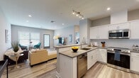 Located at 11 Lafayette Dr in New Windsor, NY, this single-floor residence offers a thoughtfully designed open-concept layout with modern finishes throughout. Light wood-style flooring flows seamlessly across the living, dining, and kitchen areas, creating a cohesive and inviting atmosphere.

The kitchen is a standout feature, equipped with white shaker cabinetry, quartz countertops, and a full suite of stainless steel appliances including a range, microwave, dishwasher, and French door refrigerator. A peninsula with seating provides both additional prep space and a casual dining option, while recessed and track lighting ensure excellent illumination.

The open living area is bright and comfortable, benefiting from natural light through large windows fitted with blinds. The space flows naturally from the kitchen, making it ideal for entertaining or everyday living.

The bedroom is generously proportioned, featuring large windows that bring in ample natural light and offer views of greenery outside. A spacious walk-in closet with built-in shelving and hanging rods provides substantial storage.

The bathroom is clean and contemporary, featuring a tiled tub-shower combination with neutral tile surround, a vanity with dark cabinetry, and crisp white fixtures that complete the polished aesthetic throughout this well-designed residence.