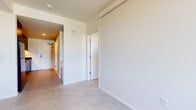 Located at 1871 N Flint Ave in Portland's vibrant North neighborhood, this three-bedroom, one-bathroom unit offers a well-organized single-floor layout designed for efficient, modern living. The galley-style kitchen makes a bold statement with sleek, floor-to-ceiling dark cabinetry, a textured dark backsplash, stainless steel countertops, and a full suite of black Whirlpool appliances including an electric range, over-the-range microwave, and refrigerator. Concrete flooring runs throughout, lending an industrial-modern aesthetic that ties the spaces together cohesively. The primary bedroom is generously sized and features a ceiling fan, a large window framing lush tree views, and a mirrored sliding closet. The two additional bedrooms are bright and functional, each offering dedicated closet space with built-in hanging rods. One bedroom benefits from an oversized window with a scenic outdoor view, filling the room with natural light. The bathroom is clean and minimal, finished in neutral tones with matte black hardware accents and accessibility-friendly grab bars. The layout flows efficiently from the kitchen corridor into the living areas and bedrooms, maximizing every square foot of this compact yet versatile space.