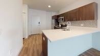 Located at 116 W 9th Street in Wilmington, Delaware, this contemporary single-floor unit offers a well-designed layout with modern finishes throughout. Rich hardwood-style flooring flows seamlessly across every room, creating a warm and cohesive aesthetic.

The open-concept kitchen is a standout feature, equipped with stainless steel appliances including a refrigerator, range, and over-the-range microwave. Dark espresso cabinetry provides generous storage and contrasts elegantly with the crisp white countertops and peninsula. A decorative tile backsplash adds a stylish finishing touch, while recessed lighting keeps the space bright and functional.

The living and bedroom areas are generously proportioned, featuring clean white walls and large windows that invite natural light and offer views of the surrounding Wilmington streetscape. A walk-in closet is accessible from the bedroom, adding practical storage.

The bathrooms continue the modern design language, with dark wood-finish vanities, framed mirrors, and white tile tub-shower combinations. One bathroom features a grab bar for added accessibility. Both bathrooms include hardwood-style flooring consistent with the rest of the unit.

Overall, this space presents a clean, contemporary feel with thoughtful design details and quality finishes throughout.