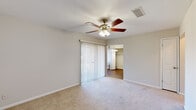 Located at 249 Oakley Dr in Columbus, Georgia, this single-floor home offers five bedrooms, one bathroom, a kitchen, a dining room, and a connecting hallway. The layout is efficiently organized, with neutral-toned walls and a mix of carpet and wood-look flooring throughout. Each bedroom features a ceiling fan with light kit, providing comfortable air circulation, and most include closets — including one bedroom with a spacious walk-in closet accessible through double doors. The primary bedroom is generously sized and includes sliding glass doors covered with vertical blinds, allowing natural light to filter in. The kitchen is equipped with white cabinetry, a tile backsplash, a double-basin sink, and black appliances including an electric range, over-the-range microwave, and dishwasher. The dining area features wood-look flooring and a large window with vertical blinds, offering views of the outdoor surroundings. The bathroom includes a tub-shower combination with full tile surround in warm earth tones, a toilet, and wood-look flooring. The hallway connects the main living areas and bedrooms in a straightforward, functional flow. Overall, the home presents a clean, practical living environment well-suited for everyday residential use.