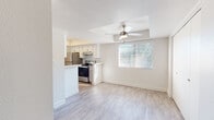 This single-floor residence offers a clean, modern aesthetic throughout, with light-toned luxury vinyl plank flooring in the main living areas and plush carpeting in the bedrooms. The open-concept layout connects the living and dining area to the kitchen, creating a bright, cohesive space. A tray ceiling with a ceiling fan anchors the living area, while a large window with blinds allows natural light to fill the room. The kitchen is designed for functionality, featuring stainless steel appliances — including a refrigerator, electric range, and dishwasher — white cabinetry with modern hardware, a subway tile backsplash, and a double-basin sink. A peninsula counter seamlessly connects the kitchen to the living space. The bedroom features a tray ceiling with a ceiling fan, a built-in closet with bi-fold doors, and a bright window overlooking greenery. The bathroom is outfitted with a single-sink vanity, ample counter space, and a full bathtub-shower combination with white tile surround. A dedicated hallway leads to an in-unit stacked washer and dryer, adding everyday convenience. Throughout, neutral wall tones and textured ceilings contribute to a clean, move-in-ready feel.