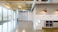 Located at 777 E Ocean Blvd in Long Beach, California, this single-floor commercial space is thoughtfully designed as a pet grooming facility with a distinctive blend of industrial and boutique aesthetics. The open main area features polished concrete floors that reflect light throughout the space, contributing to a bright and clean atmosphere. Exposed ductwork and piping run across the ceiling, lending an industrial character that is balanced by warm, decorative touches throughout.

A bold blue-and-white damask wallpaper featuring whimsical animal portraits serves as a striking focal point, adding personality and charm to the interior. White subway tile lines the walls in the grooming zones, where built-in stepped platforms and open cubbies — stocked with rolled towels — provide functional workstations. Bold red gooseneck wall sconces accent the tiled walls, adding a pop of color that ties the design together.

The entry features glass double doors etched with playful dog silhouettes, welcoming guests into the space. Floor-to-ceiling windows along one wall flood the interior with natural light and provide a clear view of an adjacent outdoor turf area, accessible via a glass door — ideal for animals to enjoy fresh air. The overall ambiance is energetic yet clean, purpose-built for pet care in a visually engaging and well-organized environment.