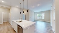 Located at 2901 Corporate Exchange Dr in Columbus, Ohio, this single-floor, 2-bedroom, 2-bathroom home offers a thoughtfully designed layout with modern finishes throughout. The open-concept living area features light hardwood-style flooring, neutral beige walls, and a large window that fills the space with natural light and outdoor views.

The kitchen is a standout feature, showcasing a large central island with a built-in sink, crisp white cabinetry, light quartz countertops, stainless steel appliances including a refrigerator, range, and microwave, and stylish pendant lighting overhead — all complemented by recessed lighting and the same warm hardwood-style flooring.

The primary bedroom is generously sized and carpeted for comfort, accompanied by an en-suite bathroom that includes a walk-in glass shower, a white vanity, and direct access to a spacious walk-in closet with wire shelving. The second bedroom is also carpeted and bright, with a large window offering outdoor views. The second full bathroom features a tub-shower combo and a white vanity with ample counter space.

A dedicated laundry room houses a full-size washer and dryer with overhead wire shelving. The home also includes two closets and a utility panel, rounding out a practical and comfortable living space.