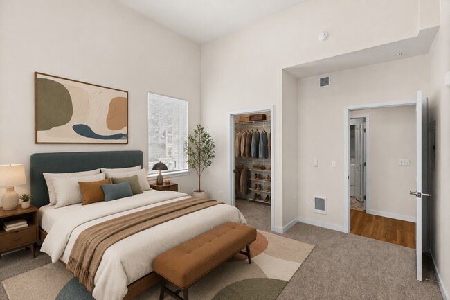 Staged bedroom showcasing the space and walk-in closet in the 841-square-foot one-bedroom Luxury floor plan. - 27 West Apartments