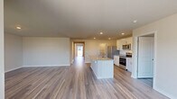 Located at 6302 Fescue Rd in Castle Hayne, NC, this single-story, 3-bedroom, 3-bathroom home offers a well-designed open-concept layout that seamlessly connects the kitchen, dining, and living areas into one expansive, light-filled space. The kitchen is a standout feature, showcasing crisp white shaker-style cabinetry, granite countertops, a large center island with a double sink, and a full suite of stainless steel appliances, including a refrigerator, range, and over-the-range microwave. An adjacent pantry provides ample storage. Wood-look plank flooring runs throughout the main living areas and hallways, lending warmth and continuity to the home. The primary bedroom is generously sized and connects to a well-appointed en-suite bathroom featuring dual granite-top vanities and a glass-enclosed shower. Two additional bedrooms offer comfortable accommodations, each with closet access. The home includes three full bathrooms in total, a dedicated laundry room with washer and dryer, an attached garage, and seven closets distributed throughout, ensuring abundant storage. Recessed lighting and neutral wall tones create a clean, modern ambiance across the entire home.
