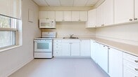 Located at 190 Cedar St in Cambridge, Ontario, this single-floor unit offers a practical and efficiently arranged layout across a modest footprint. The space is finished with warm parquet wood flooring throughout the main living and sleeping areas, lending a classic character to the interior. Suspended tile ceilings are present in several rooms, contributing to a clean, uniform appearance.

The kitchen is equipped with an ample run of white cabinetry — both upper and lower — providing generous storage. White appliances include an electric range with overhead microwave and a dishwasher, complemented by a double-basin sink. Light-toned flooring and neutral walls keep the kitchen bright and functional.

Multiple rooms feature windows fitted with roller blinds, allowing natural light to filter in while offering views of surrounding greenery. Baseboard heating units are present in the windowed rooms, ensuring year-round comfort. One room includes a dedicated closet space with built-in shelving and parquet flooring, adding practical storage capacity.

The bathroom is finished with white subway tile surrounding a full soaking tub, paired with clean white fixtures and a classic brass door handle. Throughout the unit, neutral wall tones and white trim create a consistent, understated aesthetic well-suited to a variety of uses.